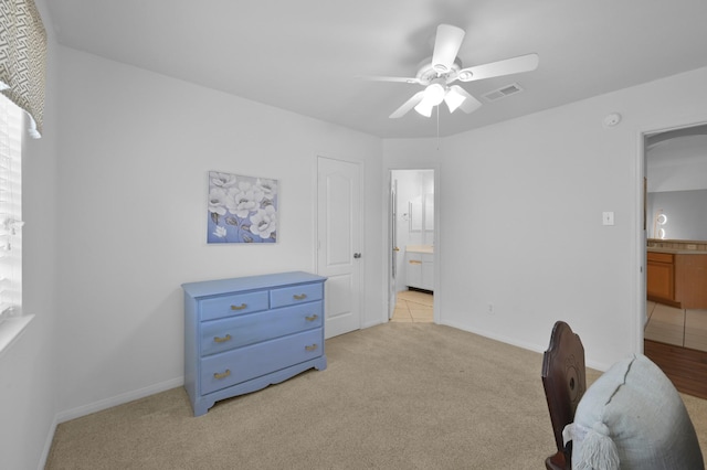 bedroom featuring light carpet, ensuite bath, a ceiling fan, and baseboards