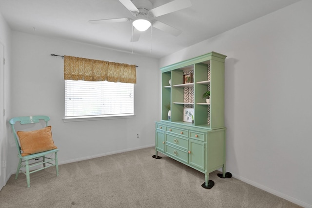 living area with light colored carpet, ceiling fan, and baseboards