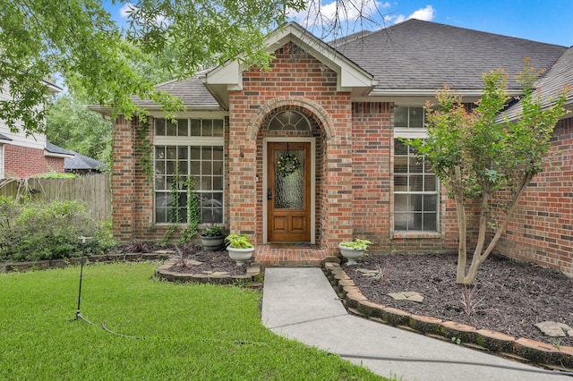 doorway to property with brick siding and roof with shingles