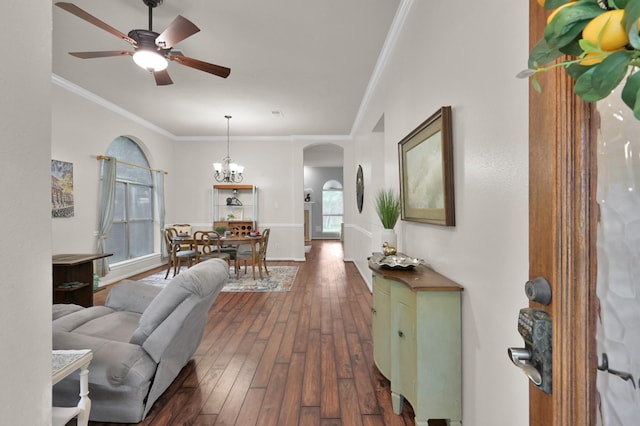 entrance foyer with arched walkways, dark wood-style flooring, ceiling fan, ornamental molding, and a chandelier