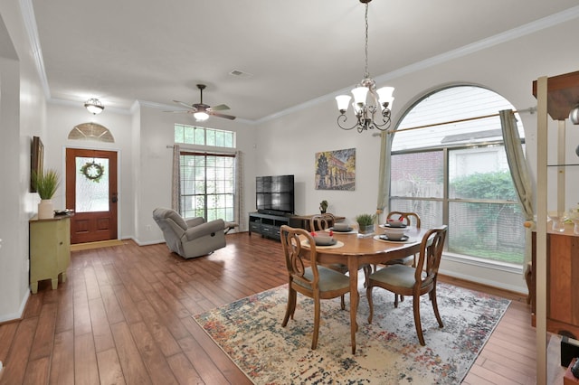 dining room with crown molding, hardwood / wood-style floors, a chandelier, a ceiling fan, and baseboards