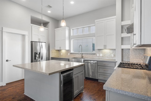 kitchen featuring wine cooler, appliances with stainless steel finishes, a sink, gray cabinetry, and tasteful backsplash