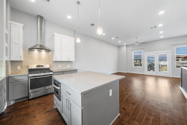 kitchen featuring gas stove, ceiling fan, gray cabinetry, backsplash, and a kitchen island
