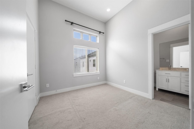unfurnished bedroom with carpet floors, baseboards, a sink, recessed lighting, and connected bathroom