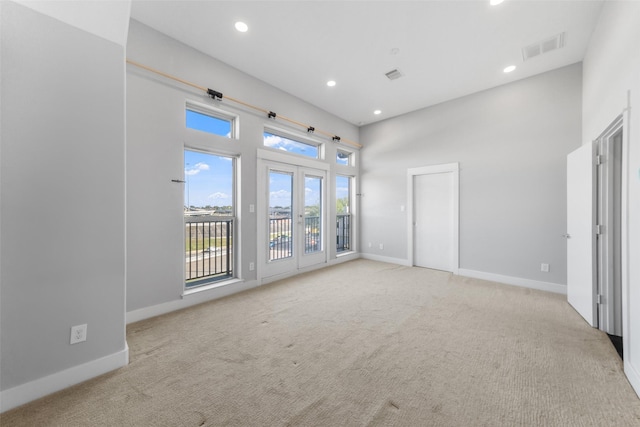 unfurnished living room featuring recessed lighting, baseboards, light carpet, and a high ceiling