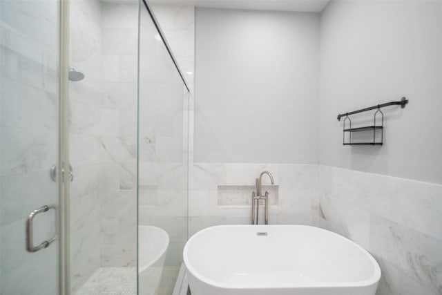 bathroom with a stall shower, a freestanding tub, and tile walls