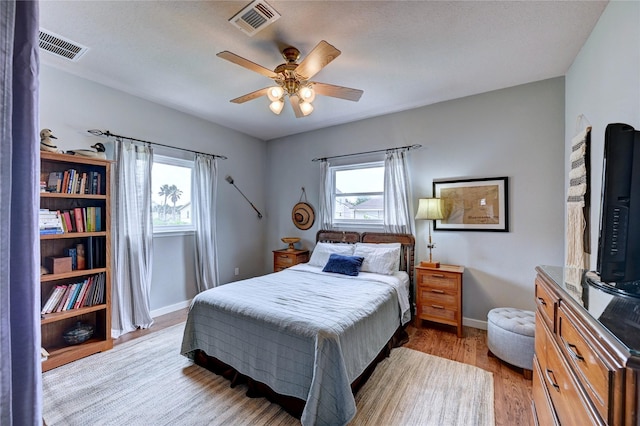 bedroom featuring multiple windows, baseboards, wood finished floors, and ceiling fan