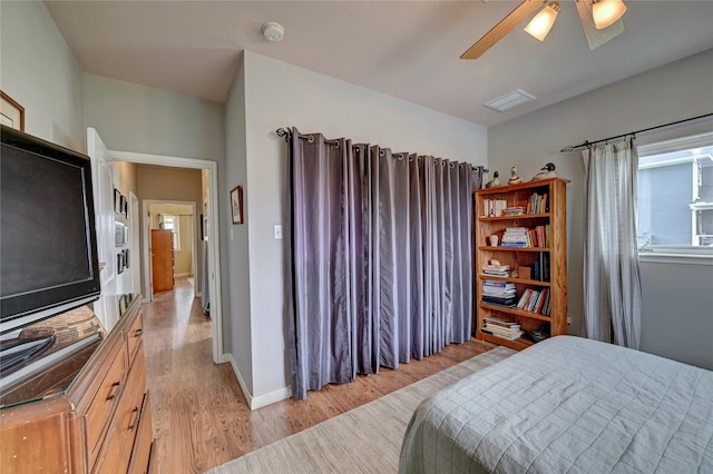 bedroom featuring light wood finished floors, a ceiling fan, and baseboards
