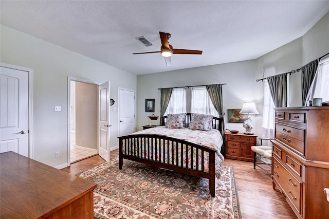 bedroom with light wood-style floors, a ceiling fan, and a textured ceiling