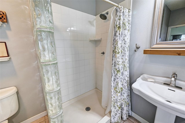 bathroom with a sink, a stall shower, toilet, and baseboards