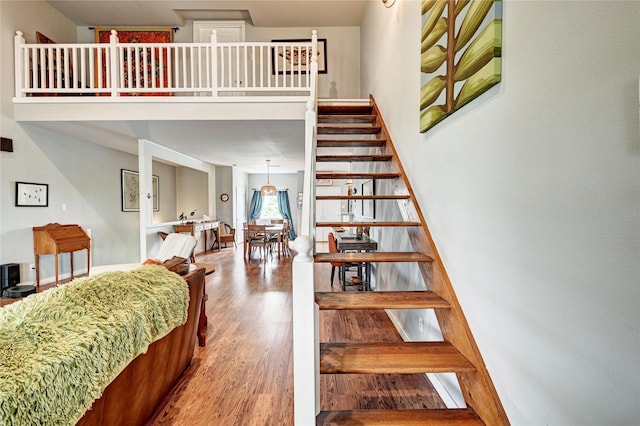 staircase featuring wood finished floors and a high ceiling