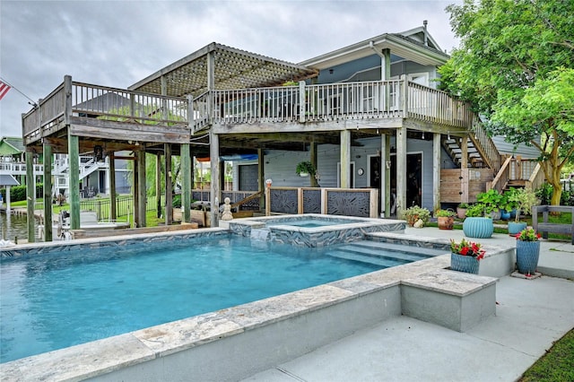 back of property featuring stairway, a deck, a patio area, and a pool with connected hot tub