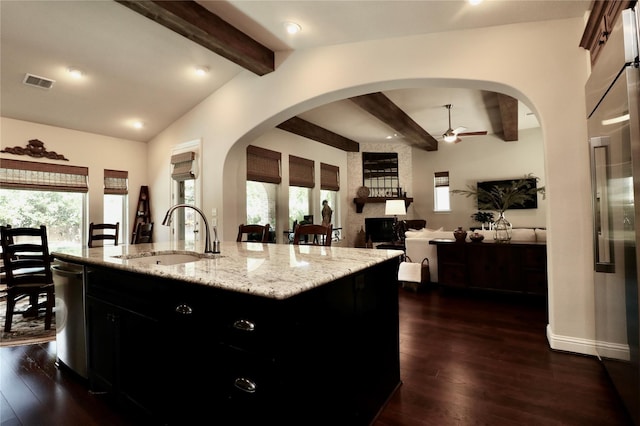 kitchen featuring a sink, ceiling fan, dark cabinetry, dark wood finished floors, and a kitchen island with sink