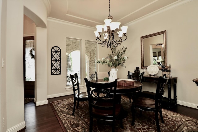 dining area with a raised ceiling, a chandelier, dark wood finished floors, baseboards, and arched walkways