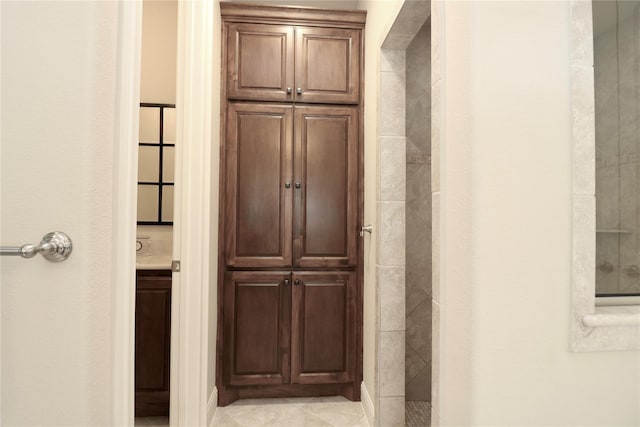 bathroom with tile patterned floors, vanity, and tiled shower