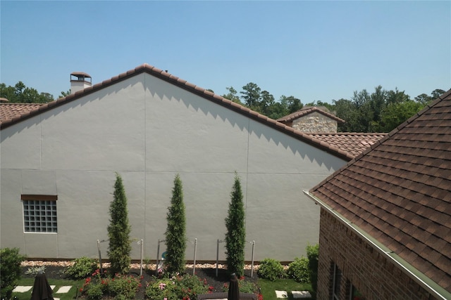view of home's exterior featuring a chimney and a tile roof