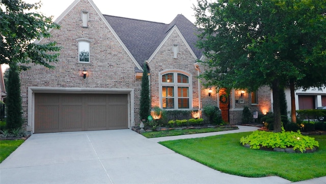 view of front of property featuring brick siding, concrete driveway, a front yard, and a garage