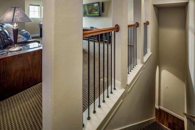 stairway featuring wood finished floors, baseboards, and a textured wall