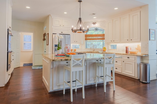 34 S Taylor Point Dr, The Woodlands, TX 77382 - kitchen with stainless steel appliances, a chandelier, backsplash, light stone countertops, and dark wood-style floors