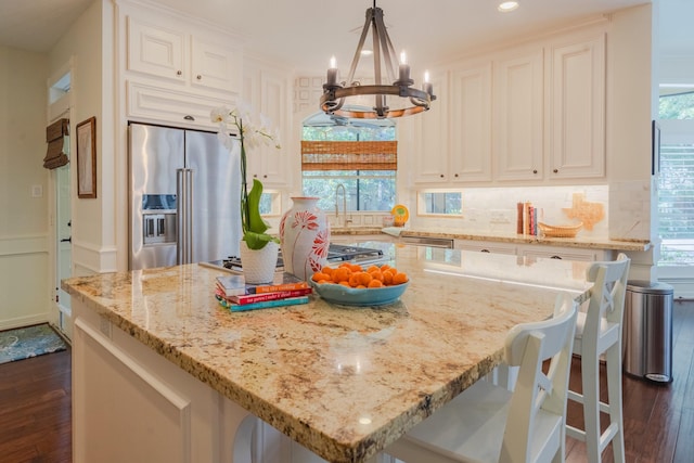 34 S Taylor Point Dr, The Woodlands, TX 77382 - kitchen featuring stainless steel appliances, dark wood-type flooring, a kitchen island, a chandelier, and light stone counters