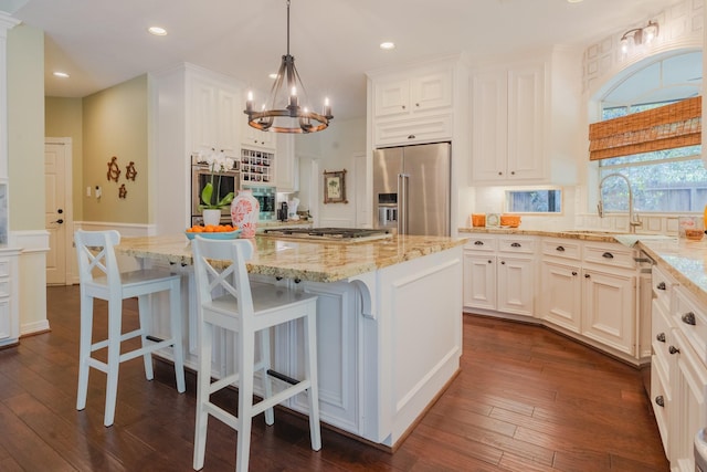 34 S Taylor Point Dr, The Woodlands, TX 77382 - kitchen featuring stainless steel appliances, a sink, light stone counters, a chandelier, and white cabinetry