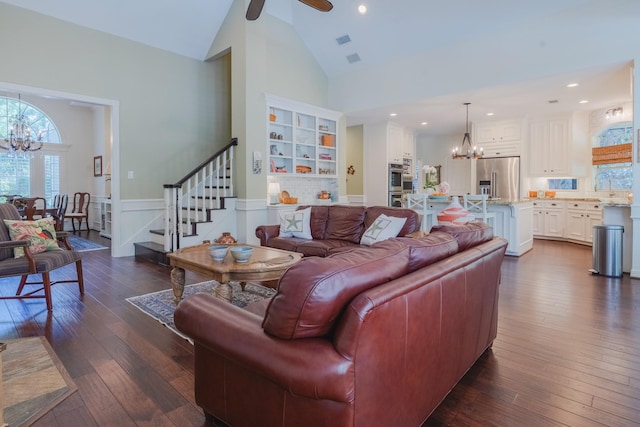 34 S Taylor Point Dr, The Woodlands, TX 77382 - living room with a chandelier, stairway, high vaulted ceiling, dark wood-style flooring, and a wainscoted wall
