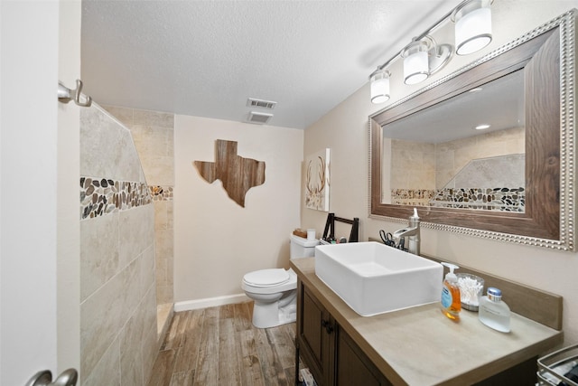79 Lakeview Vlg, Conroe, TX 77356 - full bathroom with wood finished floors, walk in shower, toilet, vanity, and a textured ceiling