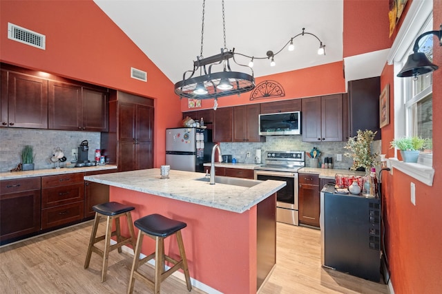 79 Lakeview Vlg, Conroe, TX 77356 - kitchen featuring appliances with stainless steel finishes, a sink, tasteful backsplash, light wood finished floors, and high vaulted ceiling