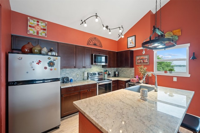 79 Lakeview Vlg, Conroe, TX 77356 - kitchen featuring appliances with stainless steel finishes, a sink, backsplash, light stone countertops, and vaulted ceiling