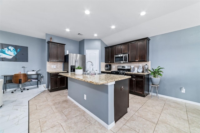 3319 Mcdonough Way, Katy, TX 77494 - kitchen with a sink, stainless steel appliances, tasteful backsplash, dark brown cabinets, and a kitchen island with sink