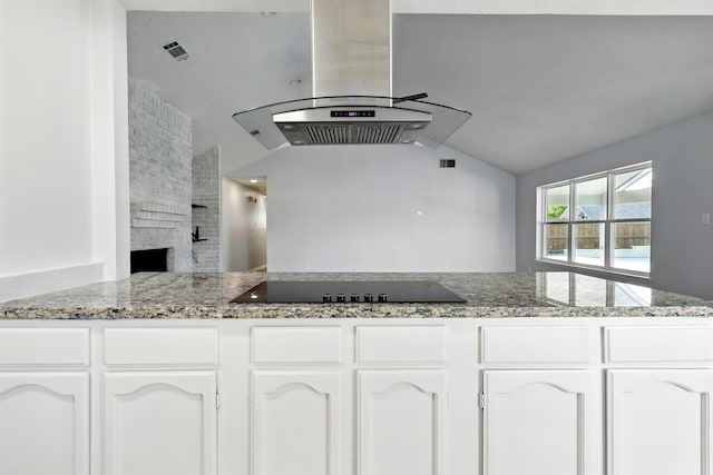 12318 Amado Dr, Houston, TX 77065 - kitchen with black electric stovetop, island range hood, lofted ceiling, white cabinets, and light stone countertops
