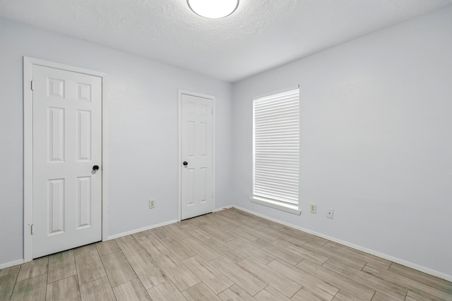 12318 Amado Dr, Houston, TX 77065 - unfurnished bedroom featuring wood tiled floors, baseboards, and a textured ceiling
