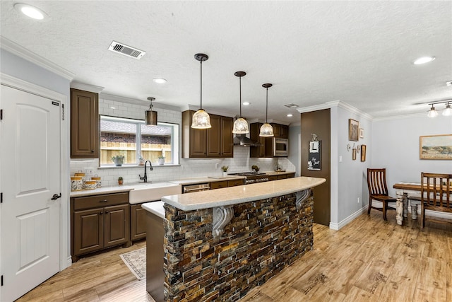 kitchen with a sink, appliances with stainless steel finishes, light countertops, tasteful backsplash, and crown molding