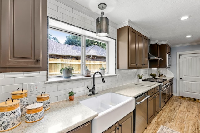 kitchen featuring a sink, appliances with stainless steel finishes, ornamental molding, backsplash, and pendant lighting