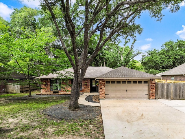 ranch-style home with a garage, brick siding, and fence