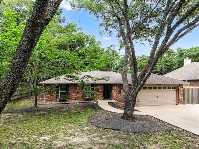 single story home with a garage, brick siding, fence, driveway, and roof with shingles