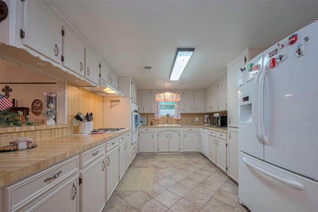 1745 15th St, Hempstead, TX 77445 - kitchen featuring white appliances, a sink, decorative backsplash, light countertops, and white cabinetry