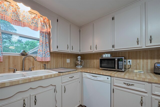 1745 15th St, Hempstead, TX 77445 - kitchen featuring white dishwasher, stainless steel microwave, a sink, light countertops, and white cabinets