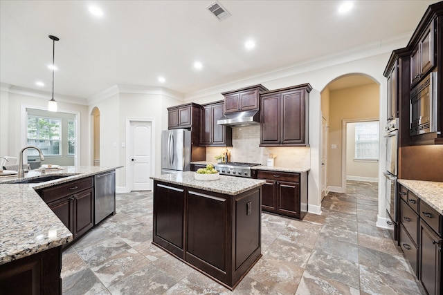 kitchen with arched walkways, a sink, stainless steel appliances, under cabinet range hood, and recessed lighting