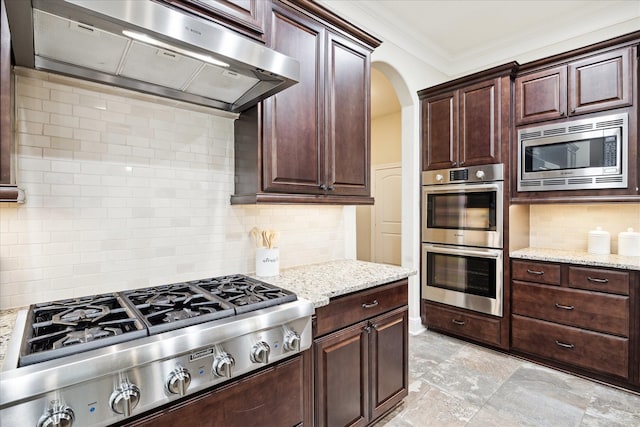 kitchen featuring extractor fan, appliances with stainless steel finishes, backsplash, ornamental molding, and arched walkways