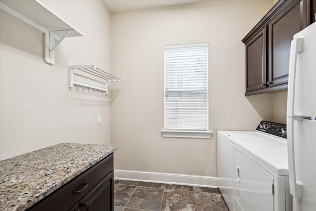 laundry area featuring washing machine and clothes dryer, baseboards, and cabinet space
