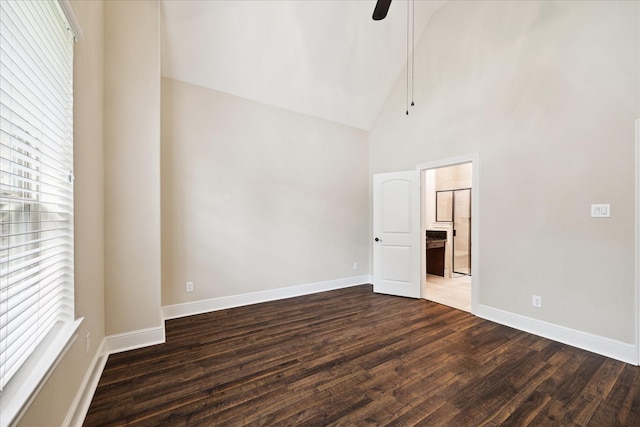 empty room with high vaulted ceiling, plenty of natural light, dark wood finished floors, baseboards, and a ceiling fan