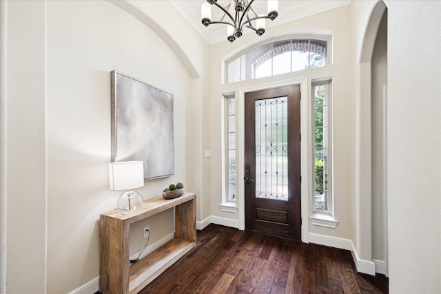 foyer featuring a chandelier, dark wood-style floors, baseboards, and ornamental molding