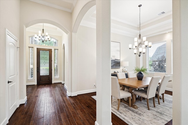 foyer entrance featuring a chandelier, dark wood finished floors, ornamental molding, arched walkways, and baseboards