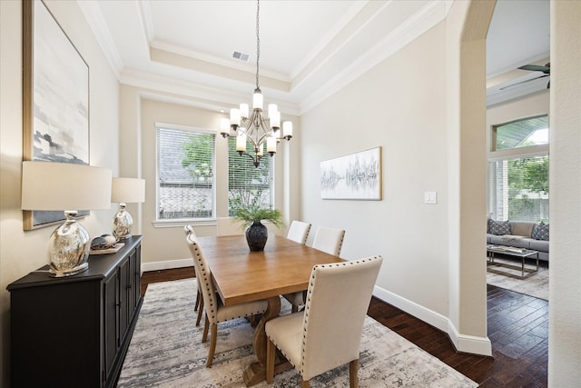 dining space with crown molding, a chandelier, healthy amount of natural light, dark wood-style floors, and a tray ceiling