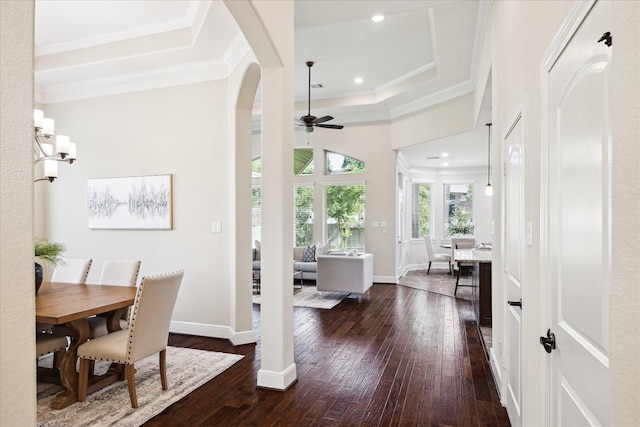 dining area featuring dark wood-style floors, ceiling fan, a tray ceiling, crown molding, and baseboards
