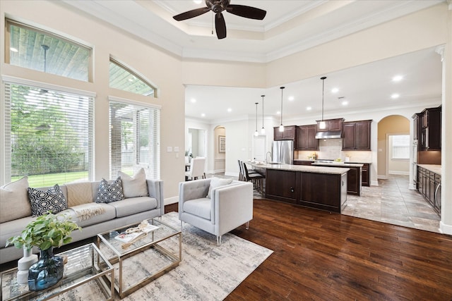 living room with crown molding, arched walkways, ceiling fan, wood finished floors, and recessed lighting
