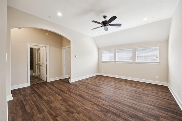 unfurnished room with arched walkways, lofted ceiling, dark wood-style flooring, a ceiling fan, and baseboards