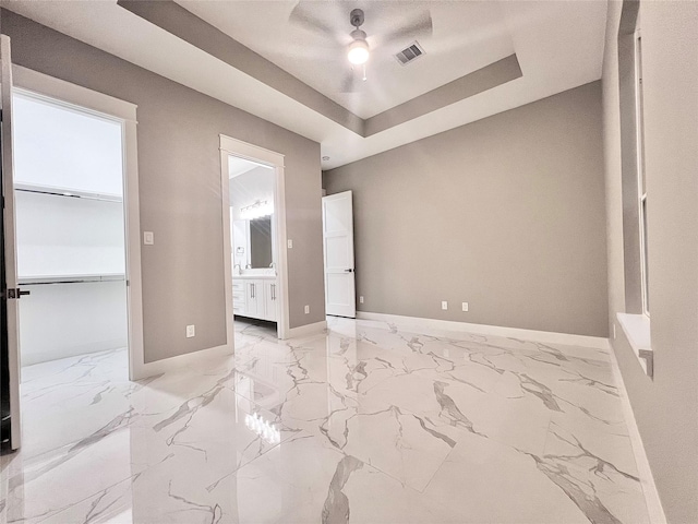 1156 Rd 6604, Dayton, TX 77535 - unfurnished bedroom featuring a tray ceiling, light marble finish flooring, baseboards, and ensuite bath