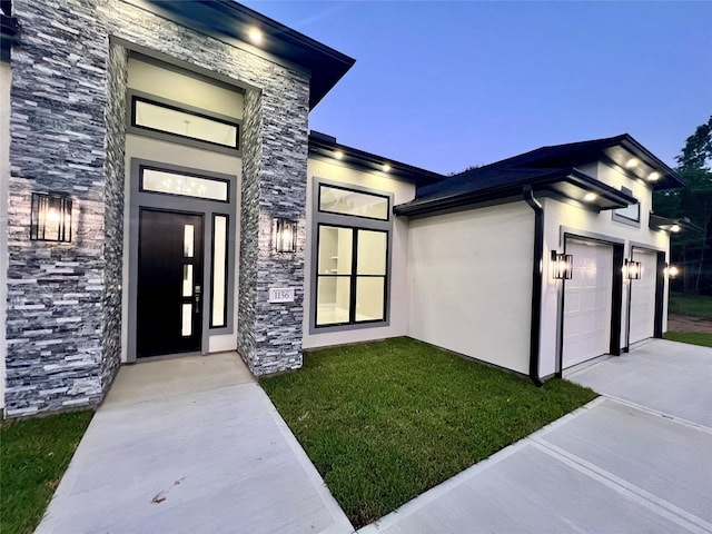 1156 Rd 6604, Dayton, TX 77535 - entrance to property featuring stone siding, an attached garage, concrete driveway, a lawn, and stucco siding